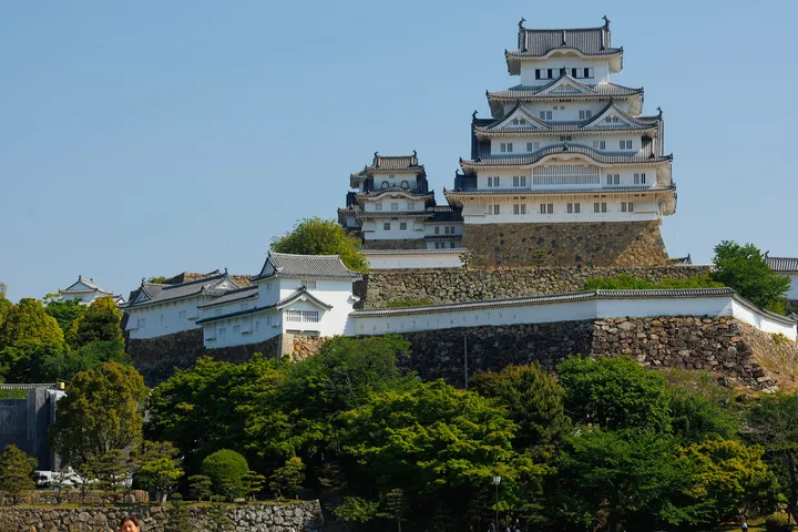 White Himeji Castle rising above stone walls and trees